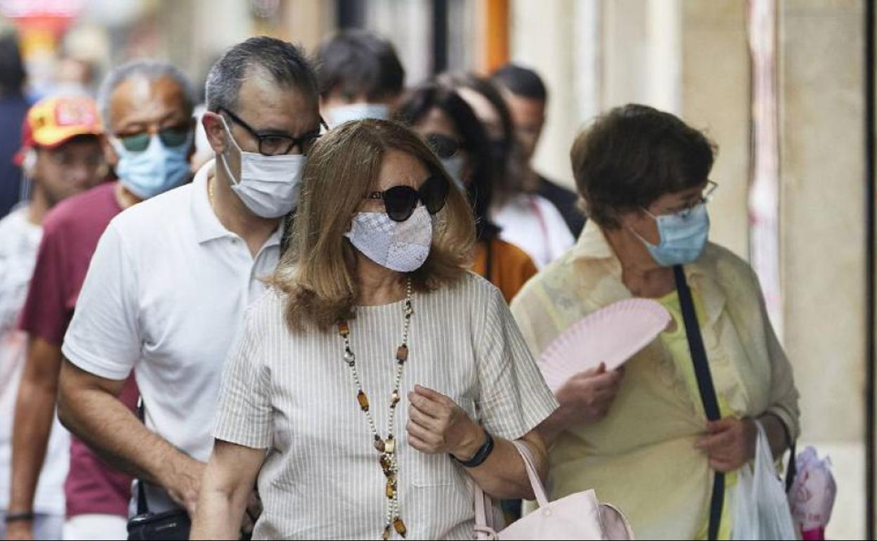 Varias personas caminan por Valencia con mascarilla.