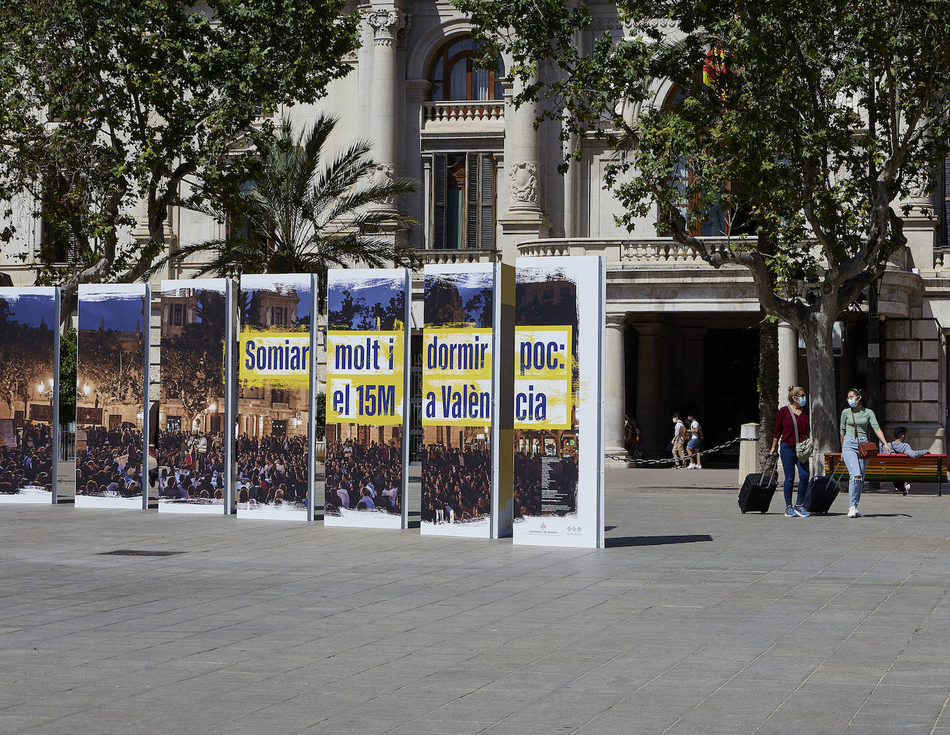 Protestas, mercadillos y restos de instalaciones se mezclan junto a la plaza del Ayuntamiento. Comerciantes y vecinos de la zona insisten en los problemas para acceder en coche mientras el monolito del 15M sigue protegido por vallas.