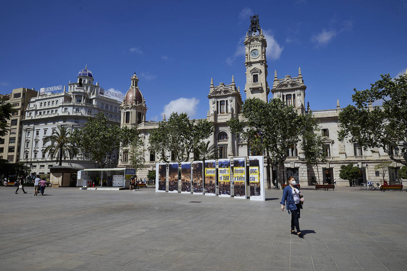 Protestas, mercadillos y restos de instalaciones se mezclan junto a la plaza del Ayuntamiento. Comerciantes y vecinos de la zona insisten en los problemas para acceder en coche mientras el monolito del 15M sigue protegido por vallas.