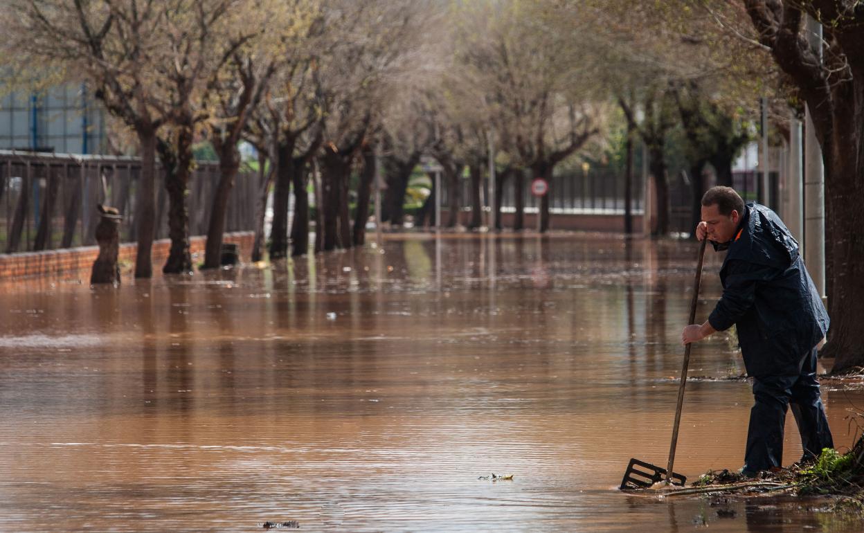 Un vecino alivia un desagüe tras una inundación en Carcaixent. 