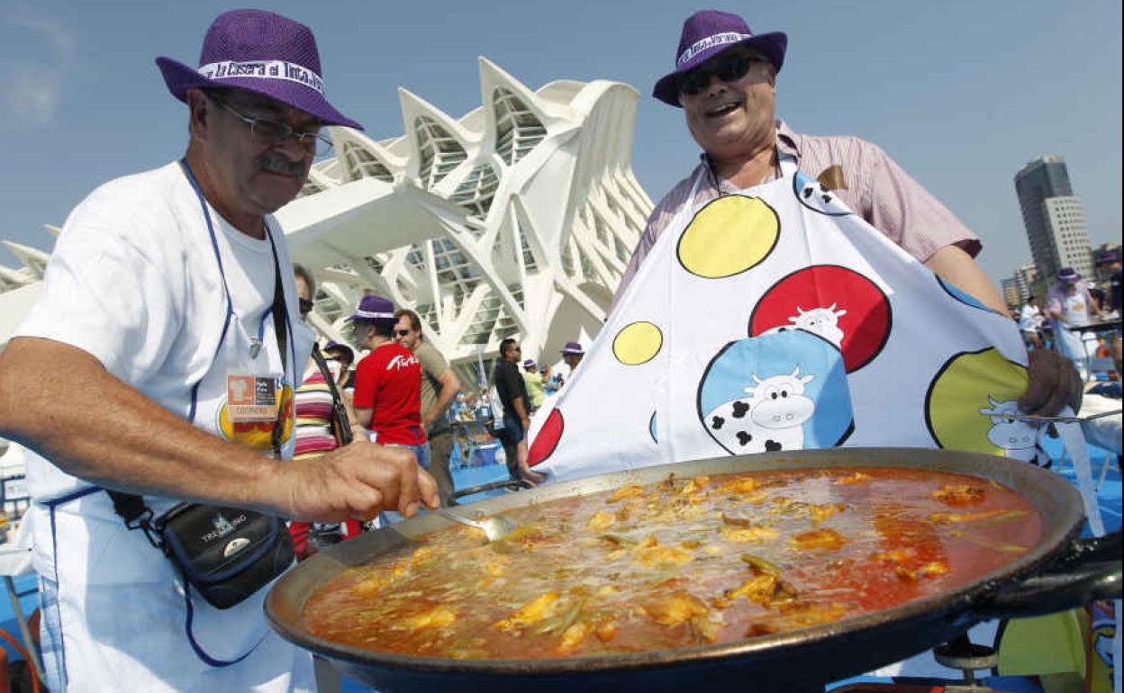 Dos hombres cocinan una paella valenciana ante el Museo Príncipe Felipe.