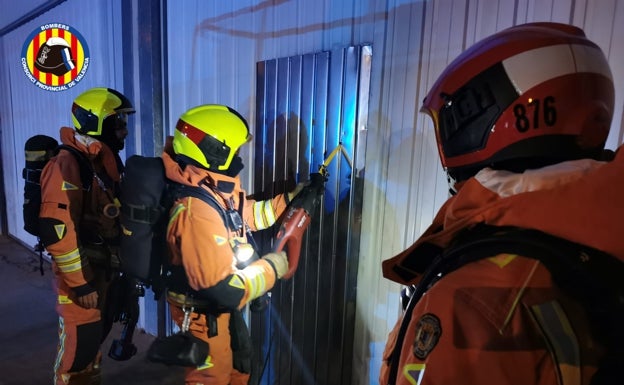 Un bombero fuerza la puerta de la empresa para sofocar el incendio. 