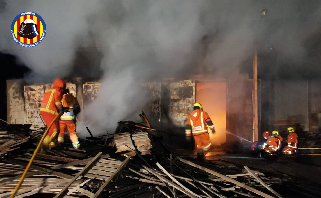 Los bomberos sofocando las llamas en la nave de Benifaió. 
