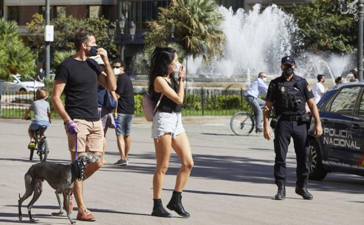 Una pareja con mascarilla en el centro de Valencia, vigilado por la Policía.