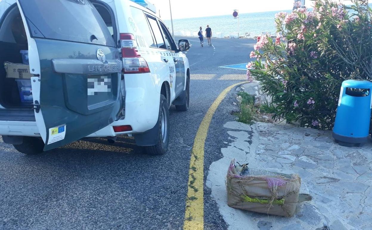 El fardo depositado en el suelo junto al vehículo de la Guardia Civil en el litoral sur de Dénia. 