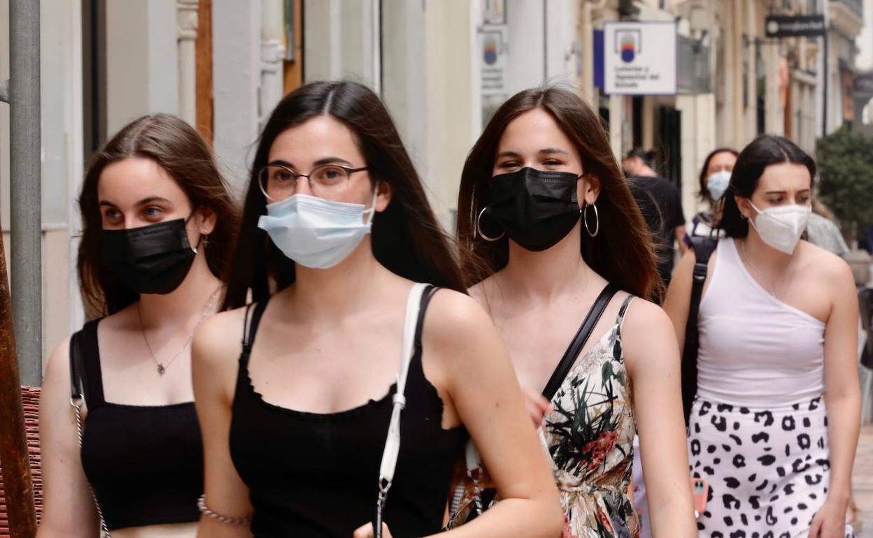 Unas chicas pasean por Valencia con la mascarilla puesta. 