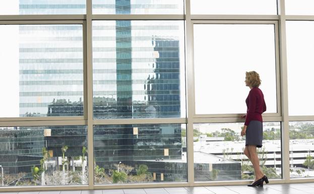 Una mujer mira por la ventana de una oficina. 