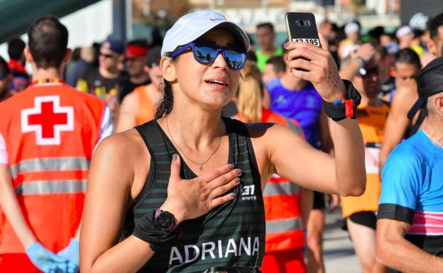 Una mujer se hace un selfie tras completar los 42K de la edición de 2019, detrás, voluntarios de la Cruz Roja. 