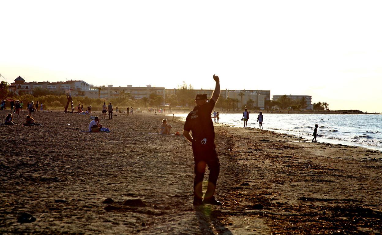 Un agente desalojando ayer la playa Punta del Raset, en Dénia. 