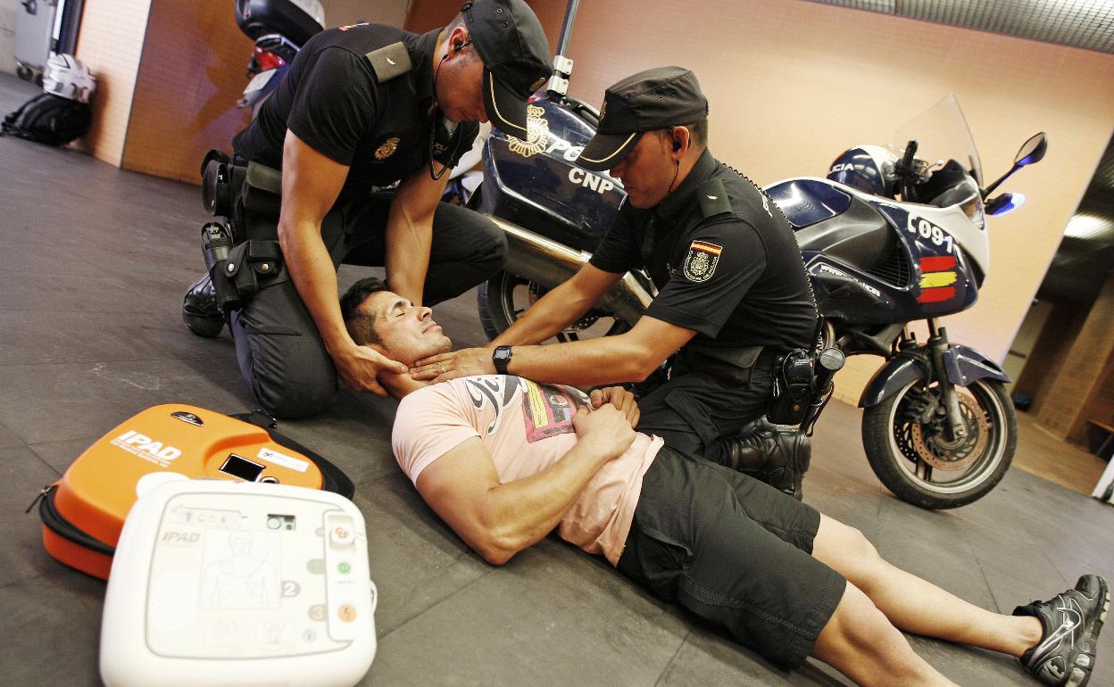 Dos policías nacionales realizan una práctica con un desfibrilador, 