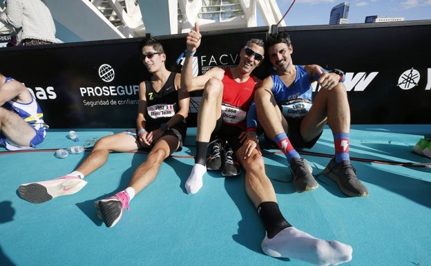 Tres corredores celebran tras haber finalizado la 10K Valencia, uno de ellos tras quitarse las zapatillas 