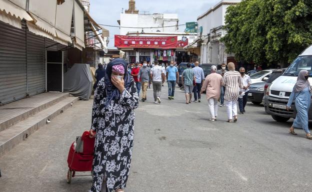 Una mujer con mascarilla camina por una calle de Rabat. (Marruecos).