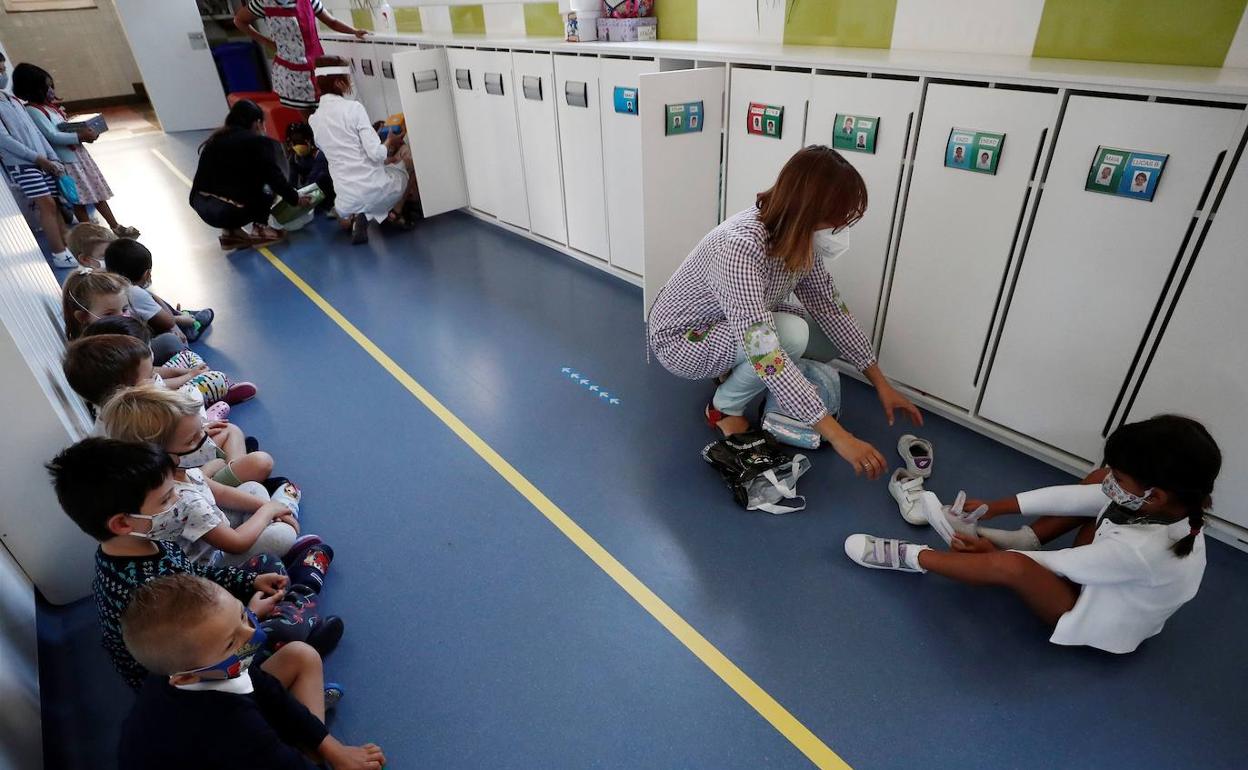 Unos niños se limpian las manos antes de entrar en clase. 