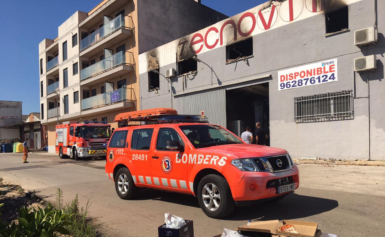 Dotaciones de bomberos apagan los últimos rescoldos del fuego en una nave de Beniarjó. 