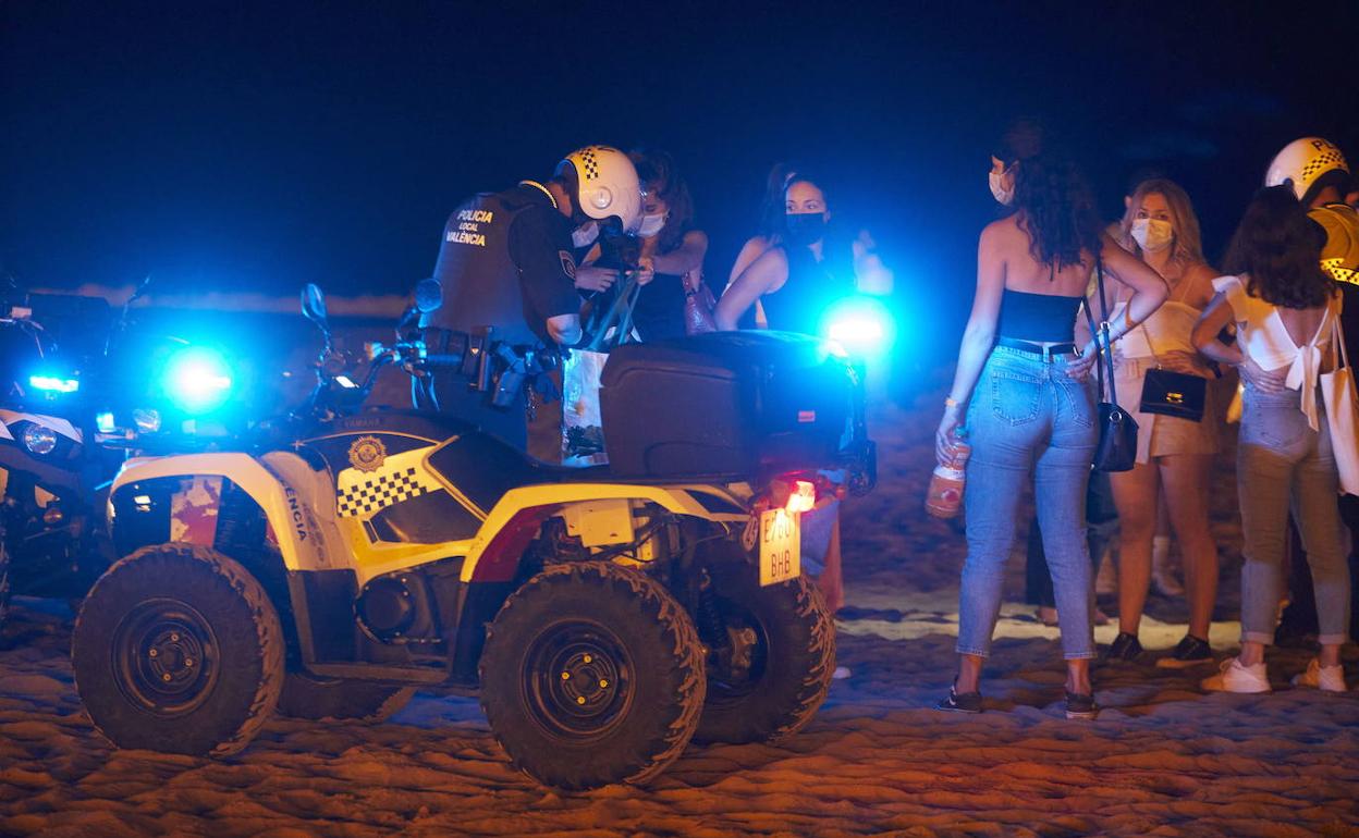 Agentes de la Policía Local junto a un grupo de jóvenes de botellón en la playa del Cabanyal, en una imagen de archivo. 