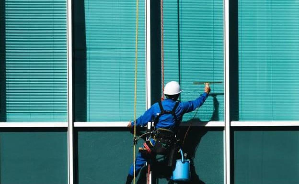 Un trabajador limpia las ventanas de un edifico.