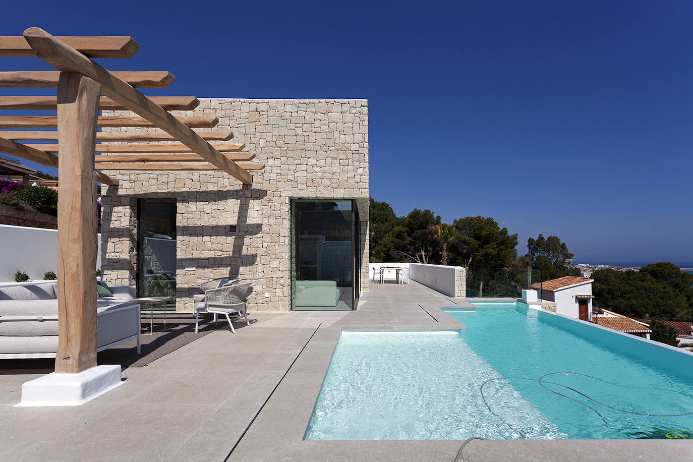 Un porche que se puede cubrir ofrece una zona de descanso junto a la piscina.