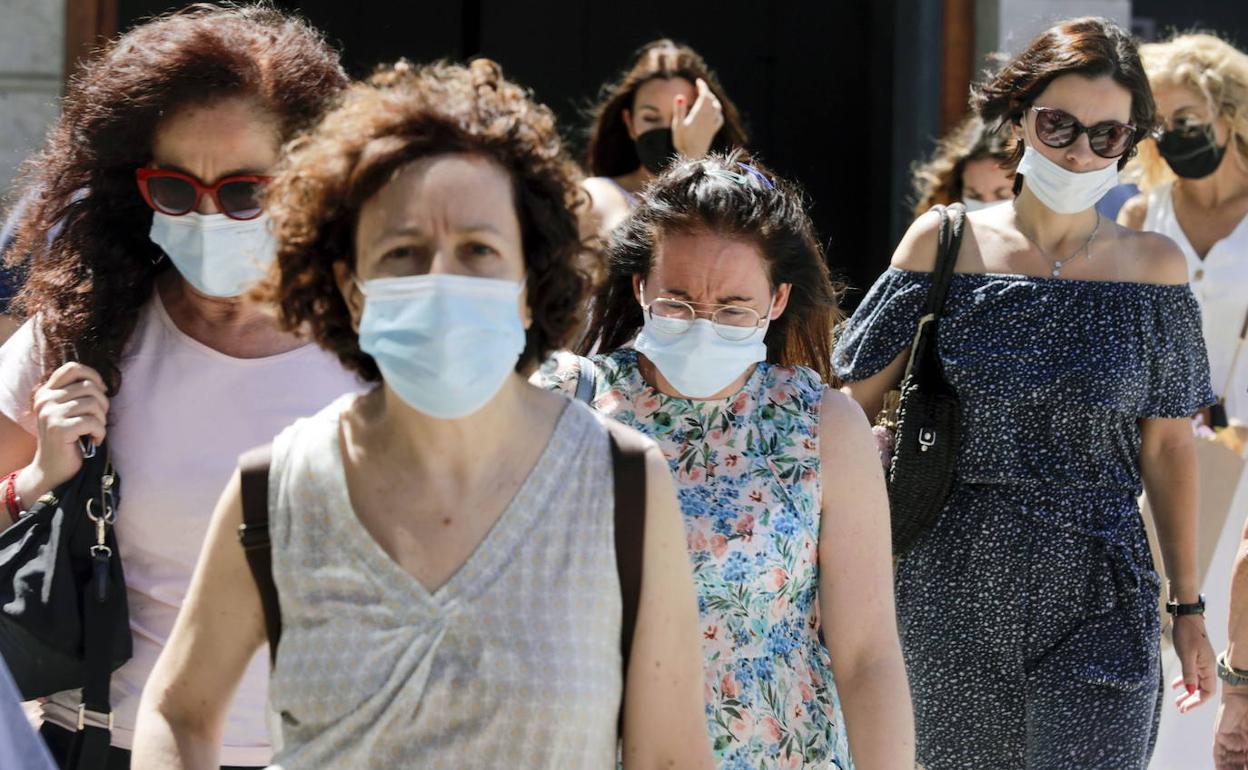 Varias personas pasean por Valencia con mascarilla. 