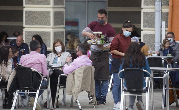 Un camarero atiende a los clientes en la terraza de un bar. 