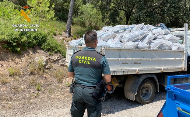 Un guardia civil junto a un camión con sacos de marihuana. 