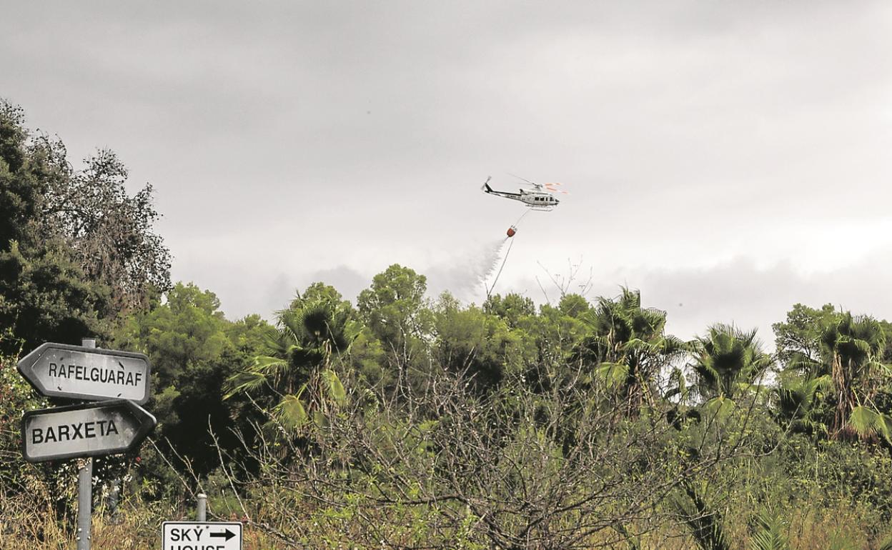 Un helicóptero descarga agua en la zona quemada. 