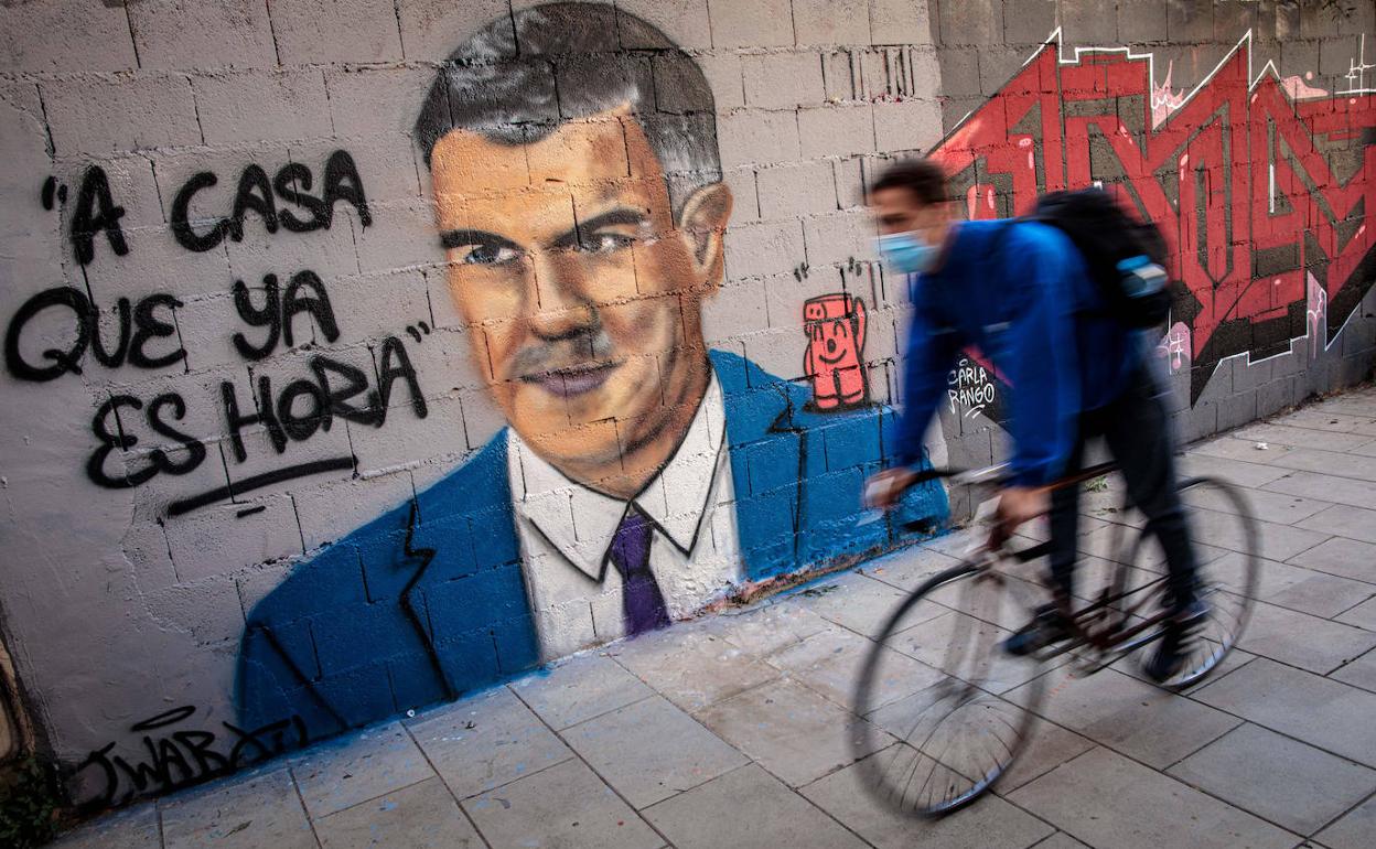 Ciclista pasando por una pintada de Pedro Sánchez en Valencia 