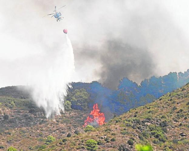 Un helicóptero descarga agua sobre las llamas en Soneja.