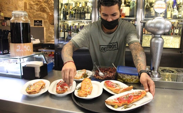 Imagen principal - Varias tostadas del Bar Mercat y clientes de La Paraeta con un trozo de tortilla  de pescado dentro del bocata. 