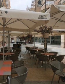 Imagen secundaria 2 - Arriba, terraza del restaurante Mahora Bistró. Abajo a la izquierda, fachada del local y valla con el logo. Abajo a la derecha, macetas del restaurante cuelgan de las sombrillas. 