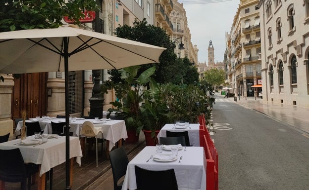 Imagen principal - Arriba, terraza de Los Gómez Taberna con el Ayuntamiento de fondo. Abajo a la izquierda, detalle del jarrón decorativo de una de las mesas. Abajo a la derecha, fachada del restaurante. 