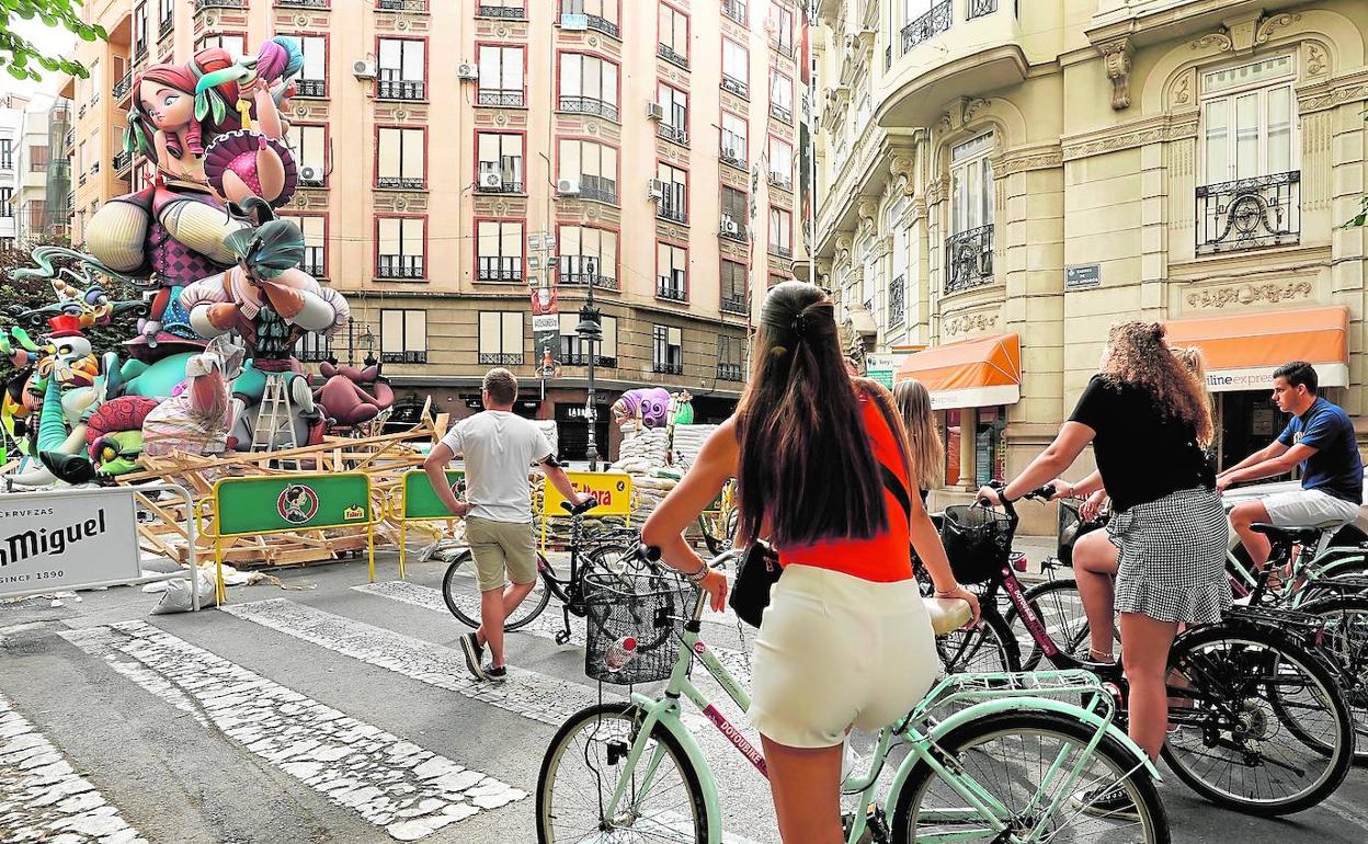 Un grupo de turistas en bicicletas contemplan la plantà de una falla en Valencia