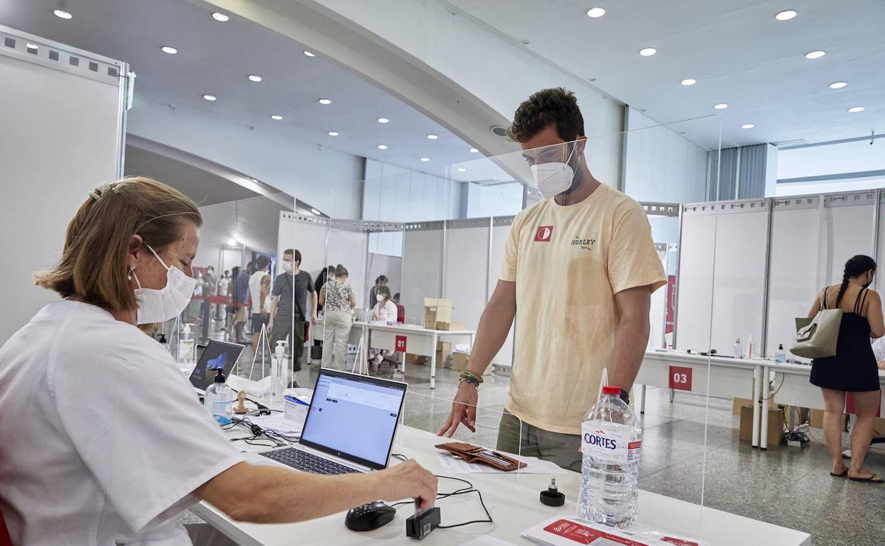 Una sanitaria realiza la tramitación previa antes de la vacunación de un joven.