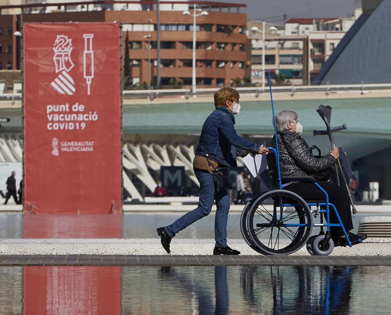 Una persona acompaña a otra con movilidad reducida al centro de inmunización masiva de la Ciudad de las Artes y las Ciencias. iván arlandis