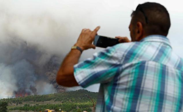 Un hombre graba las columnas de humo tras la erupción del volcán. 