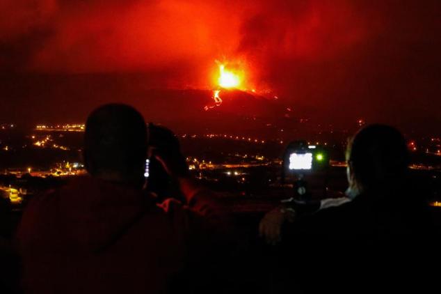 Varias personas observan la boca eruptiva del volcán. 