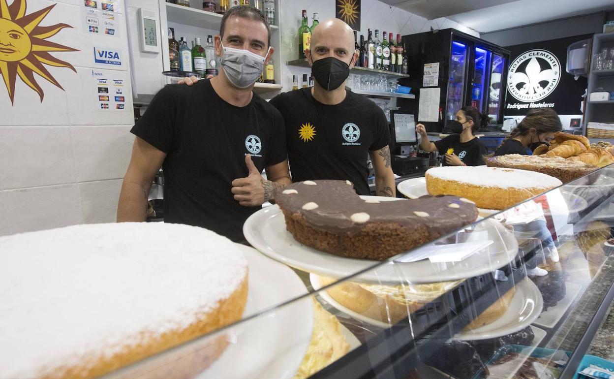 Matías y Martín Rodríguez, detrás de una de las vitrinas del bar que regentan, donde tienen una gran variedad de tartas hechas con harina de almendra y aptas para celíacos.