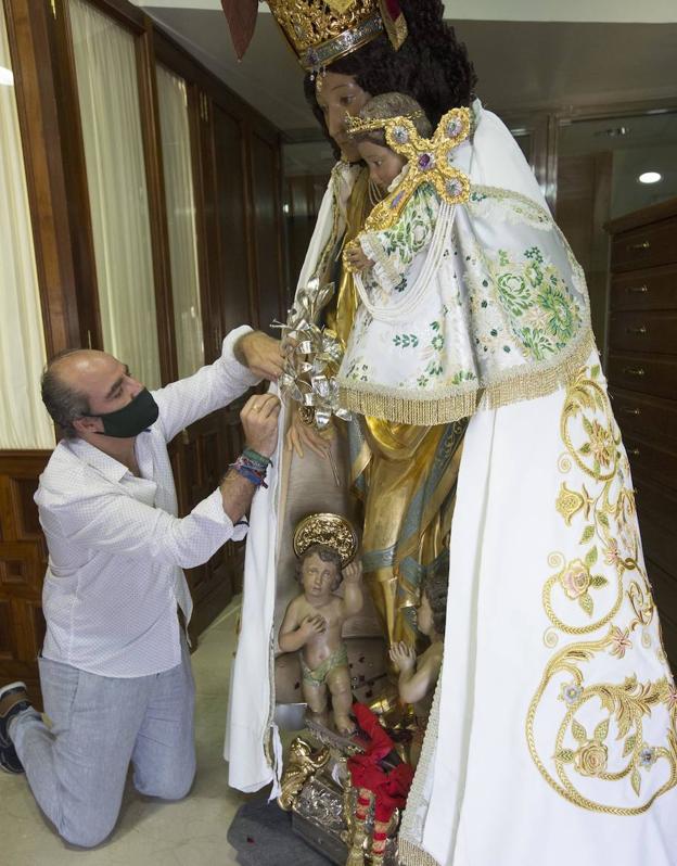 Perales sujeta con agujas el manto de solidaridad, en tono blanco sobre la talla de la Peregrina. 