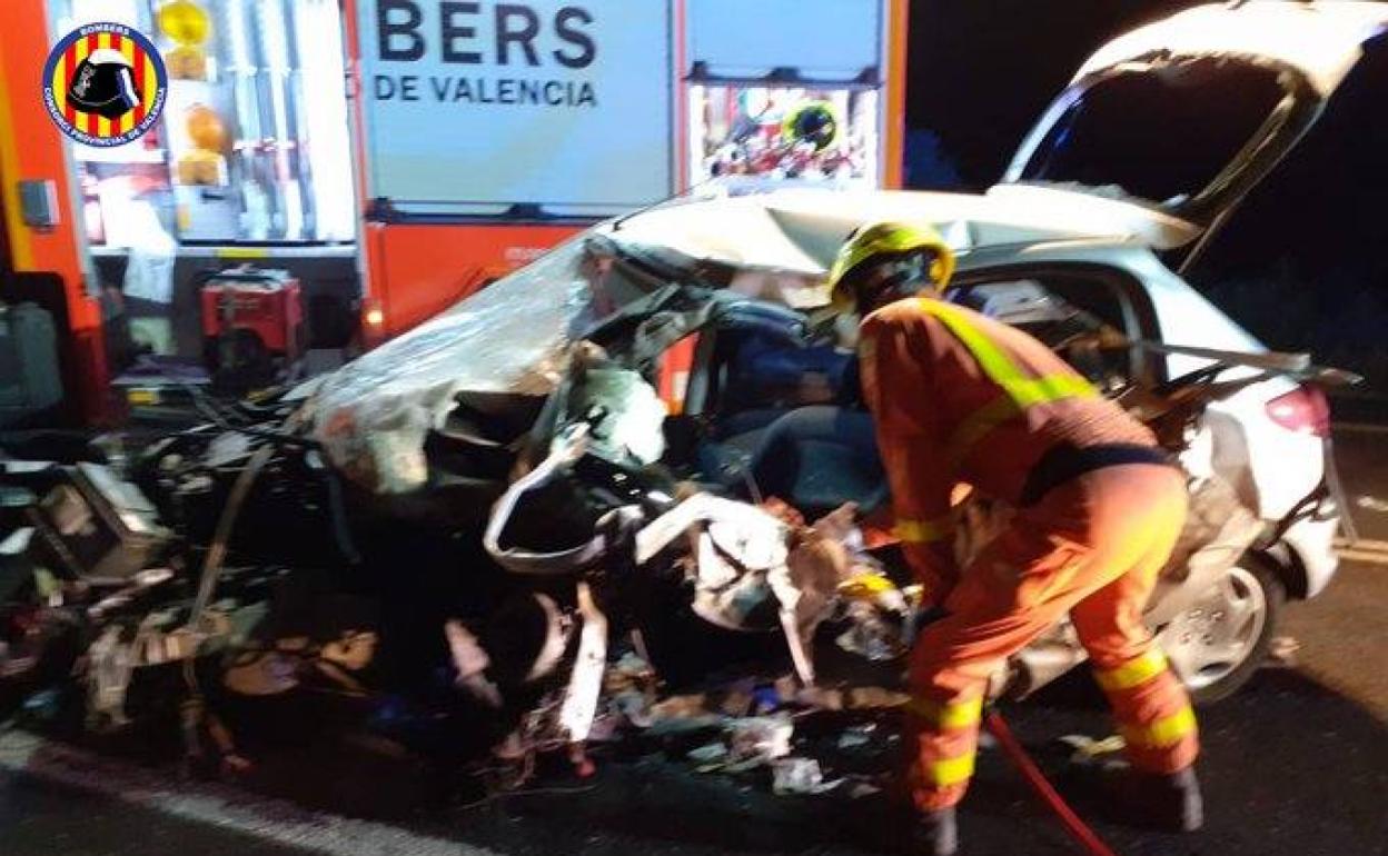 Bomberos del Consorcio Provincial de Valencia, junto al coche destrozado en el que viajaba la joven. 