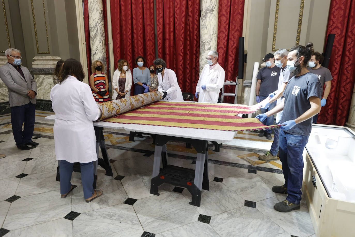 Cuatro meses de restauración devuelven el brillo a la enseña de 1928, que procesionará el 9 d'Octubre. Los expertos comprueban que el azul grisáceo que corona la pieza responde al mismo tono que muestra la bandera del siglo XVI