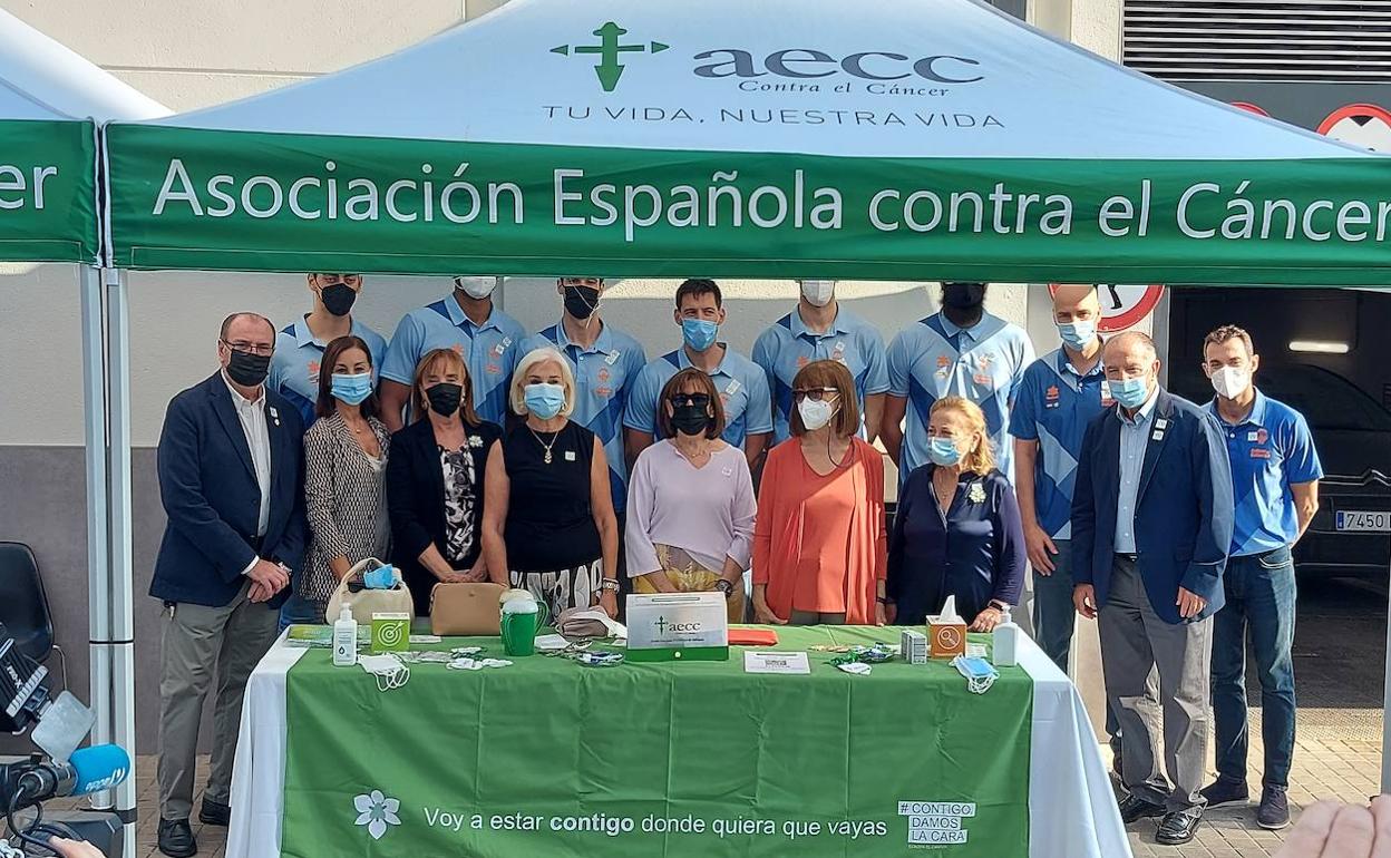 Foto de familia de la delegación del Valencia Basket junto a la mesa de cuestación en favor de la AECC.