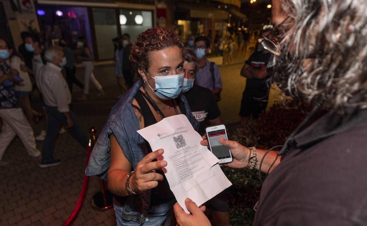 Una mujer muestra un certificado con sus vacunas contra el COVID-19 en regla para acceder a un local.