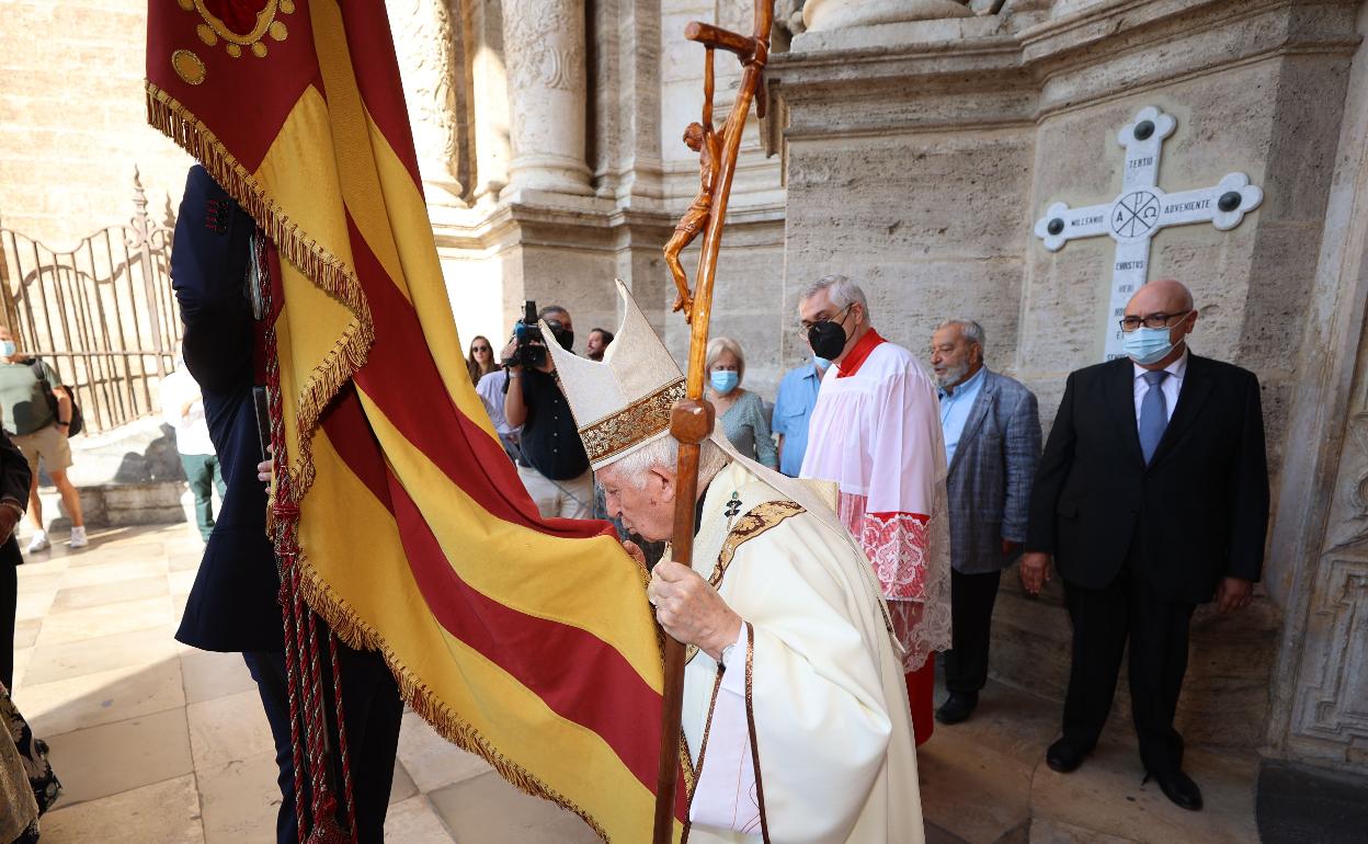 El cardenal Antonio Cañizares besa la Senyera de Lo Rat Penat a su llegada a la catedral. 