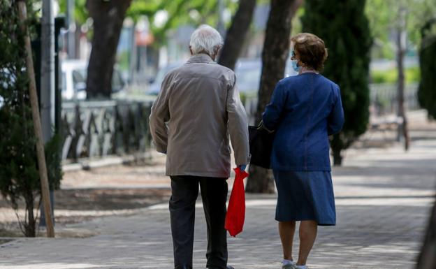 Dos ancianos pasean por un parque. 