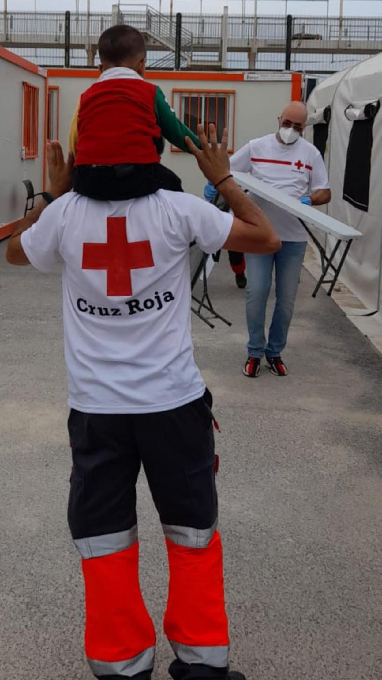 Un miembro de Cruz Roja lleva a hombros a uno de los menores llegado en los últimos días en patera. c. roja