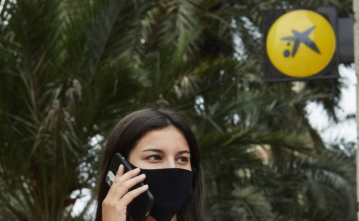 Al fondo, una oficina de Caixabank en Valencia. 