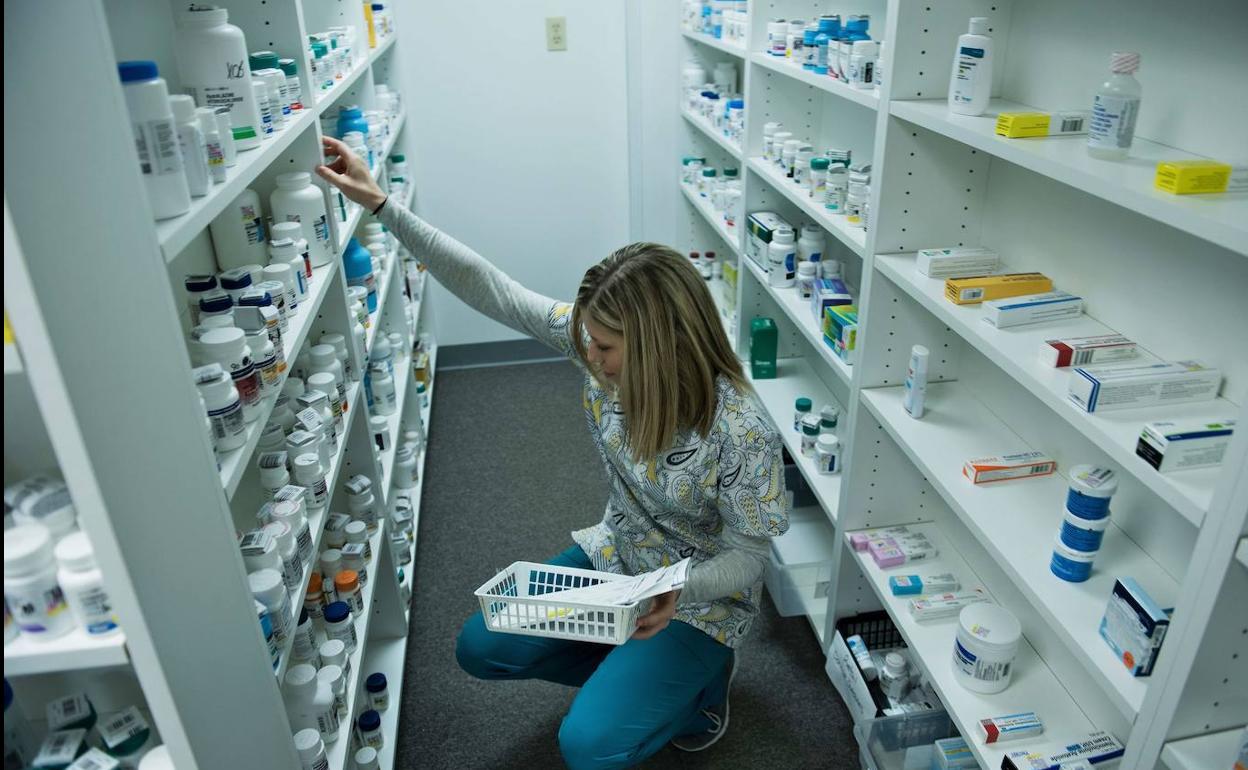 Farmacéutica buscando medicamentos en las baldas de la farmacia