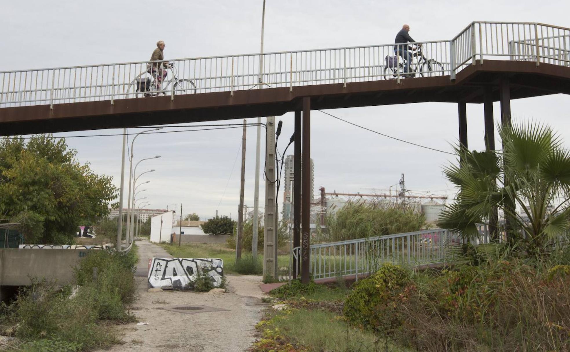 El paso. Los turistas en su ruta hacia El Saler, cruzan el barrio por la pasarela. 