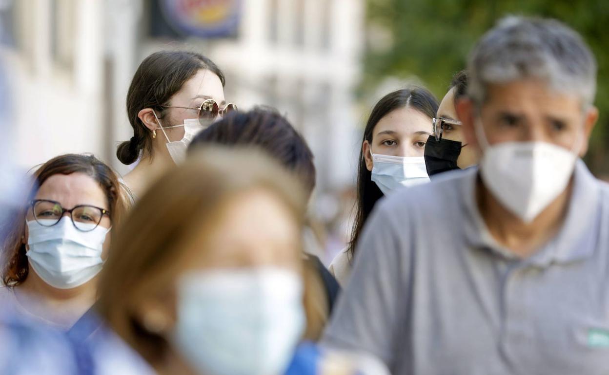 Varias personas paseando con mascarilla en Valencia. 