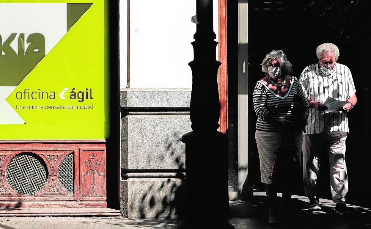 Dos personas caminan junto a una sucursal bancaria en Madrid. 