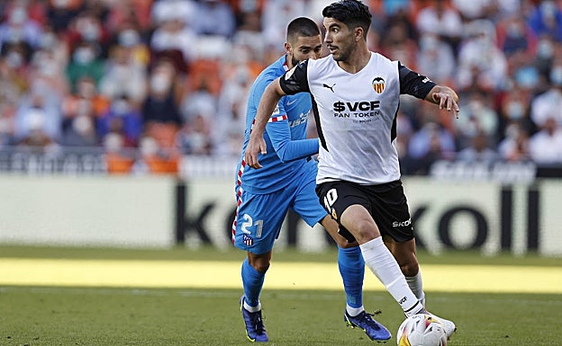 Carlos Soler controla el esférico ante la presión del atlético Carrasco. 